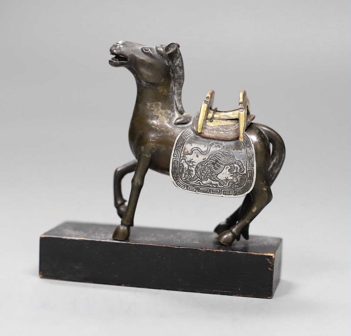 A Chinese bronze mixed metal figure a saddled horse, late 19th/early 20th century, wood stand, 8.5cms high